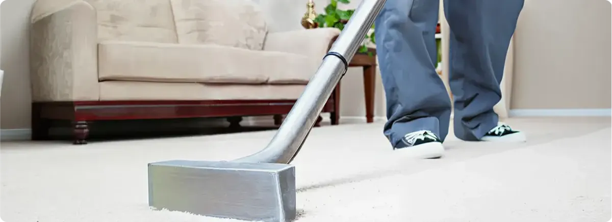 Carpet cleaning technician using a hot-water extraction wand on a light-colored carpet in a living room, Fort Lauderdale, FL.